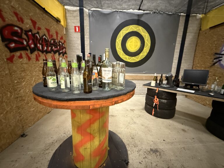 Binnenkant van een smash room bij The Rage Eindhoven met flessen, elektronica en target wall